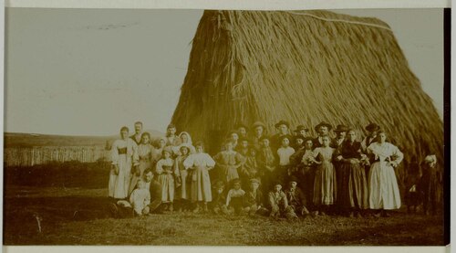 Gruppo di contadini in posa di fronte a una capanna