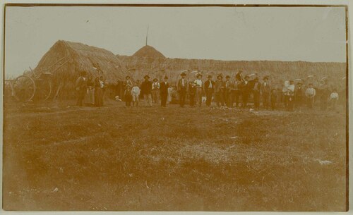 Gruppo di contadini con falci di fronte a un capannone dell'Osa