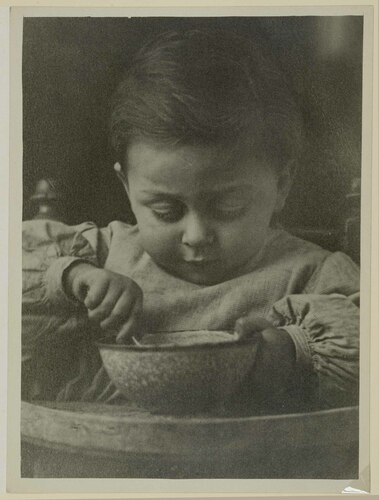 ritratto di bambino sul sediolone intento a mangiare